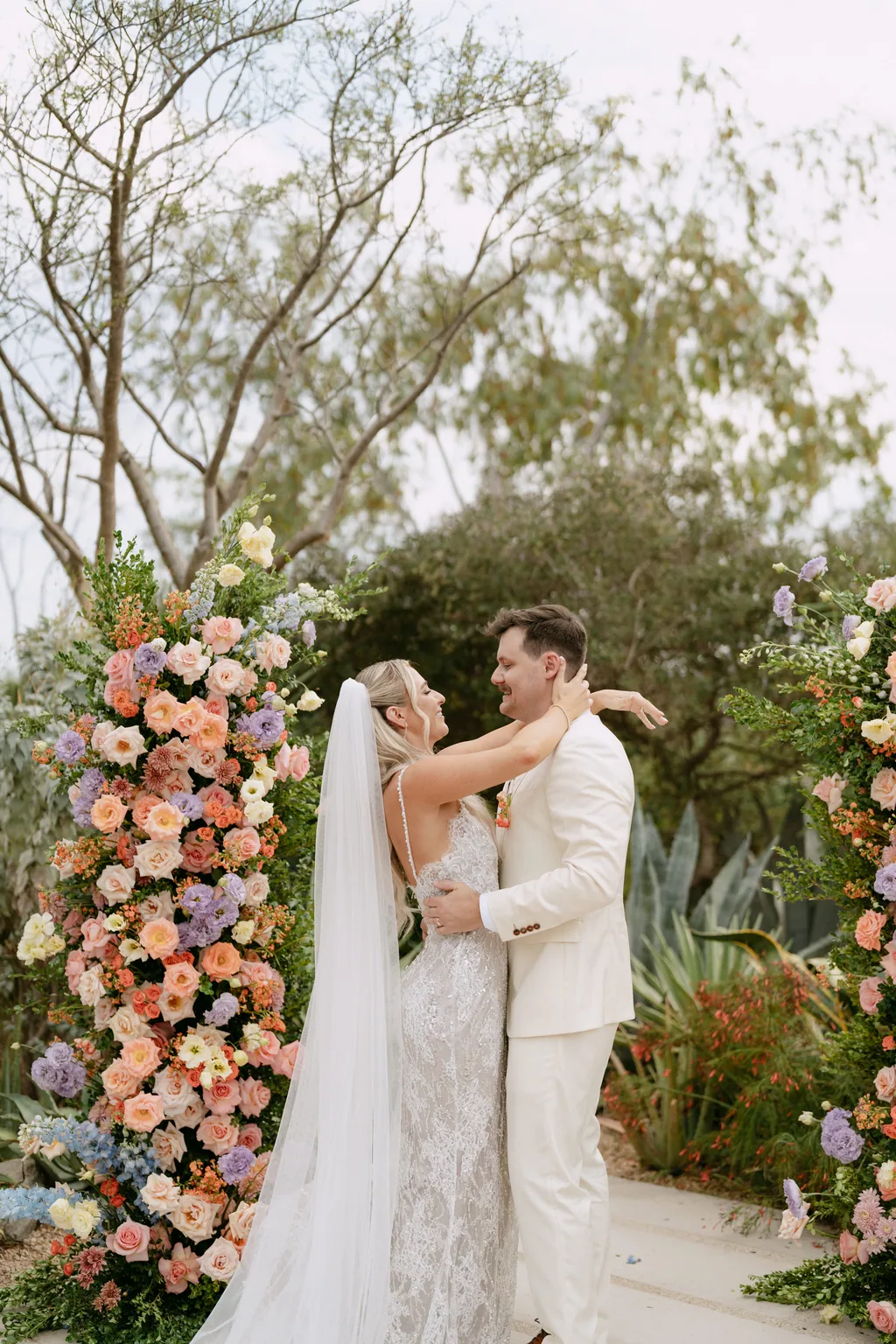 Bailey and Matthew hold each other under the flower arch after their ceremony at Acre