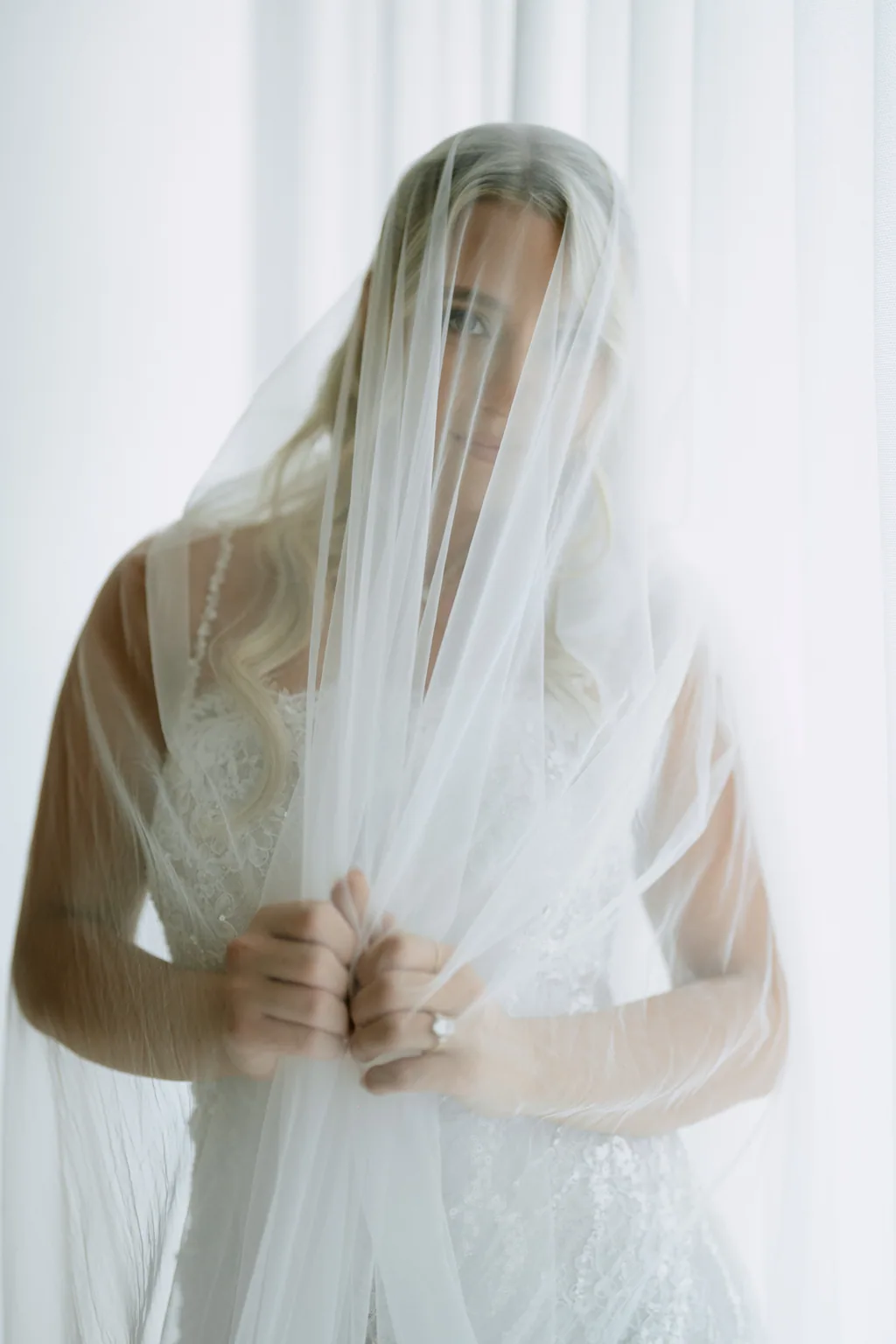 Bailey under her veil, hands together, before the ceremony
