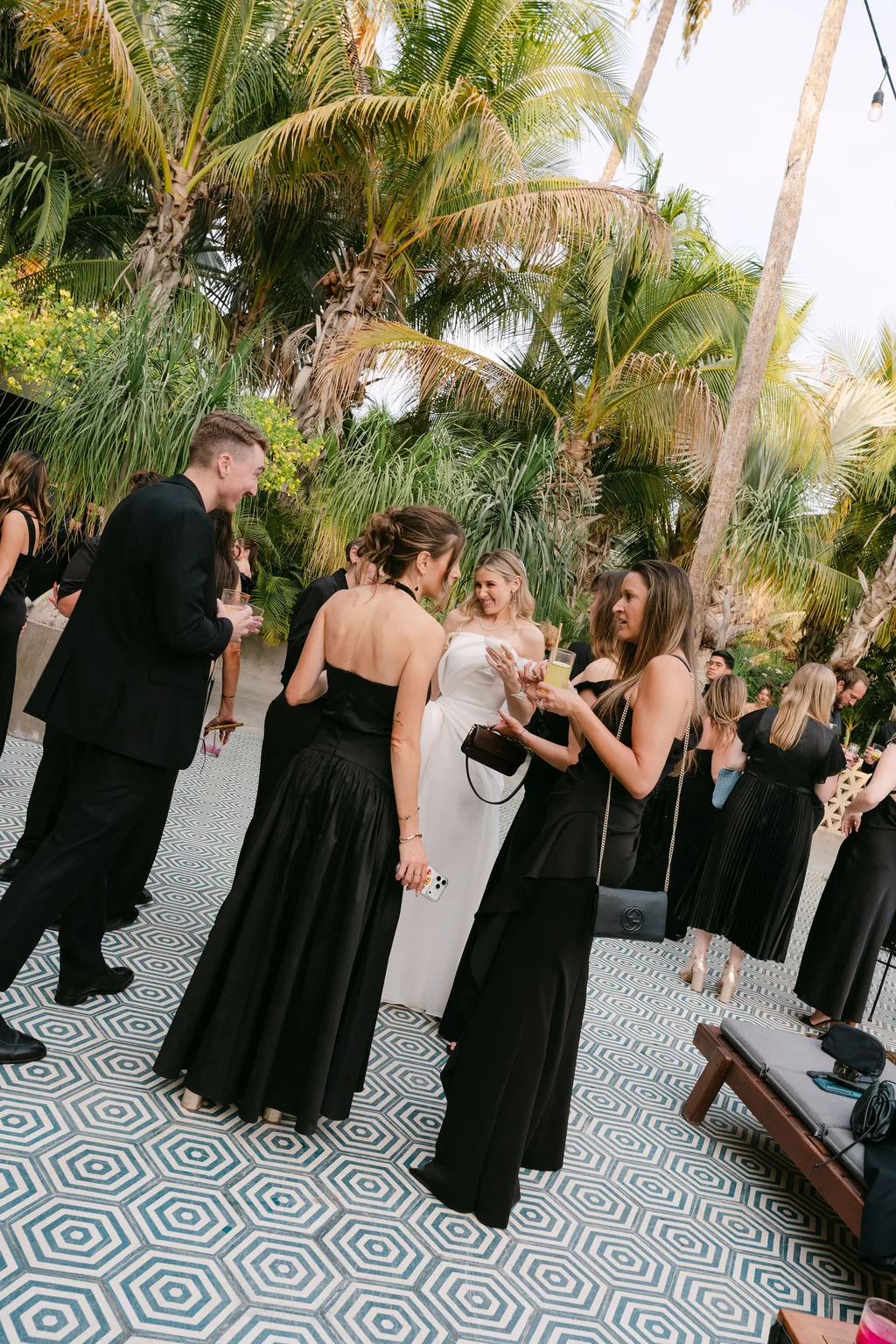 The bridesmaids in black gathered around them by the pool