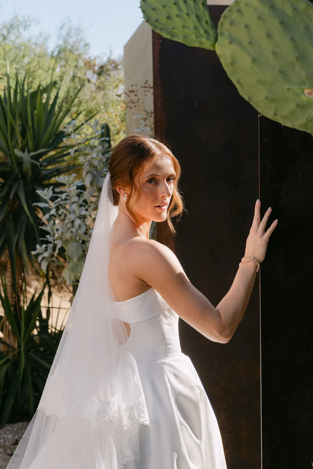 Lauren with her hand on the steel wall in the cactus garden at Acre
