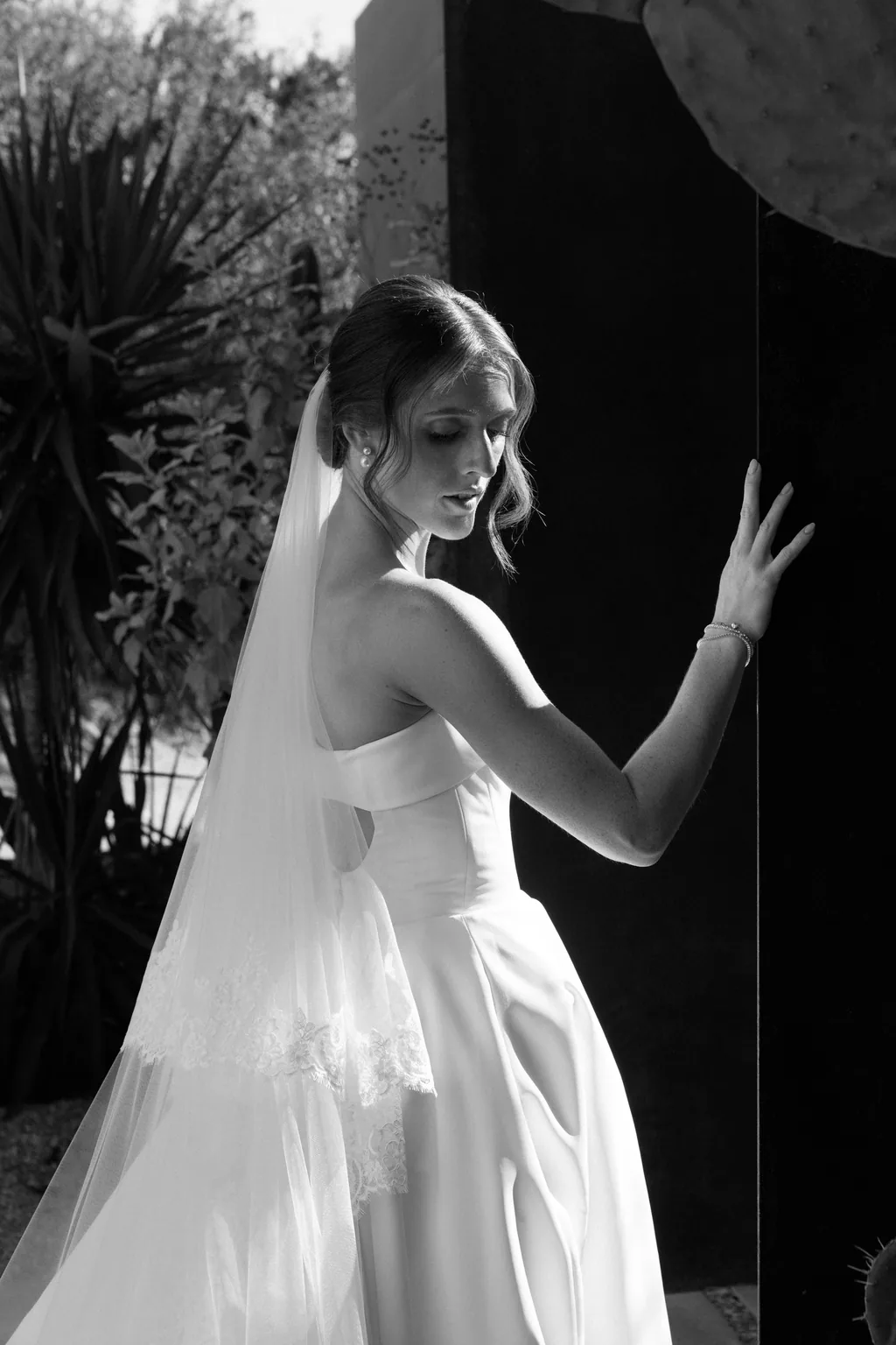 Lauren against a black doorway with her arm raised, in black and white