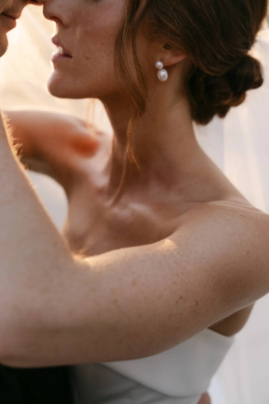 Her shoulder and her earring under the veil in the sun