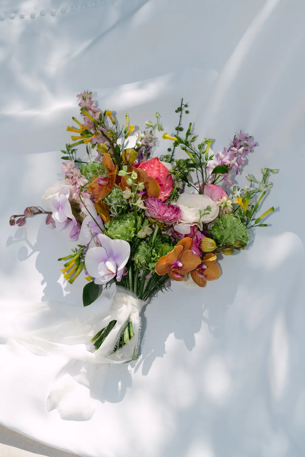 Her bouquet in a vase against a white wall, with the shadow of a leaf